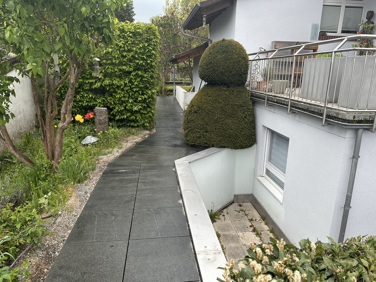 Ein gepflegter Gartenweg mit beschnittenen Büschen und einem weißen Haus.