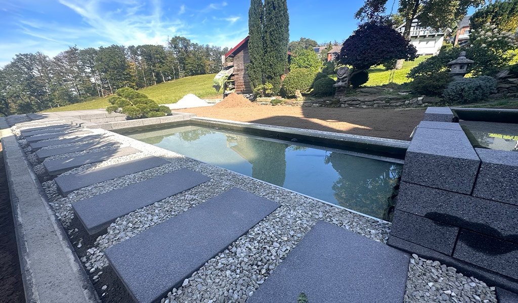 Ein gepflegter Garten mit einem rechteckigen Teich und einem malerischen Himmel im Hintergrund